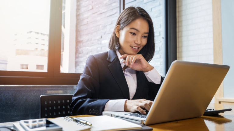 Closeup of businesswoman using laptop at office desk. She searching web or browsing information.